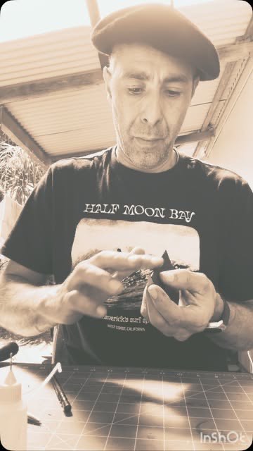 The maker working a small piece of leather at the bench.