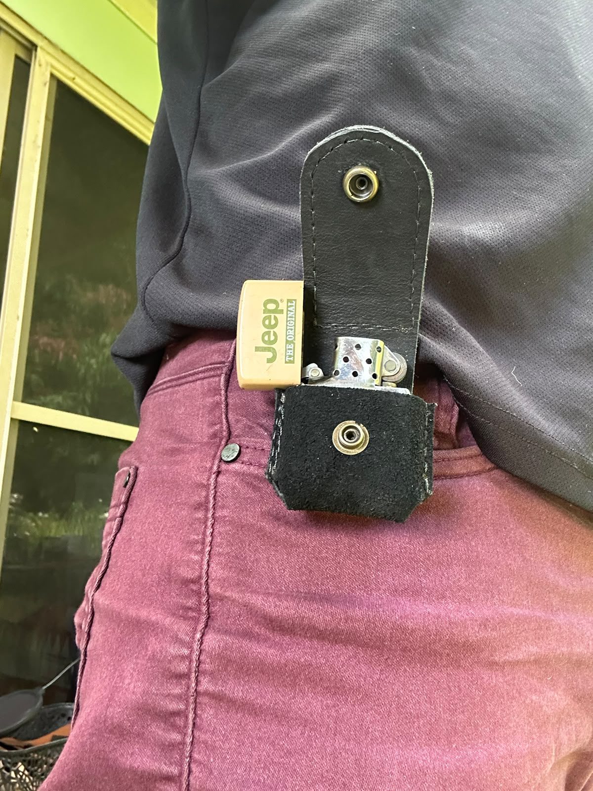 A black leather lighter case clipped to a belt.